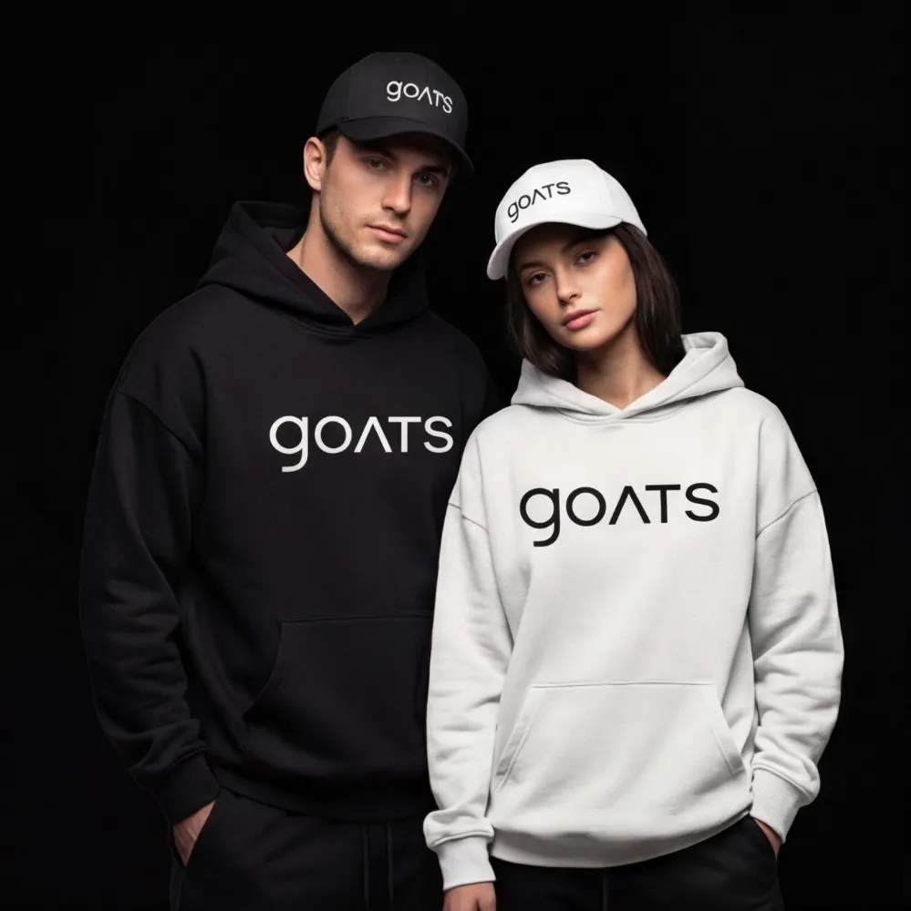 A man and a woman in matching black and white GOATS hoodies and caps